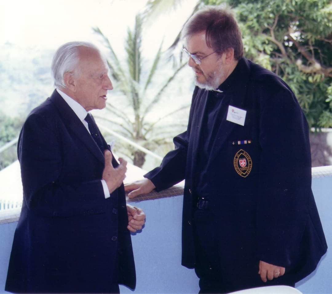 Grand Master Fra’ Andrew Bertie speaking with Father Gérard T. Lagleder outdoors